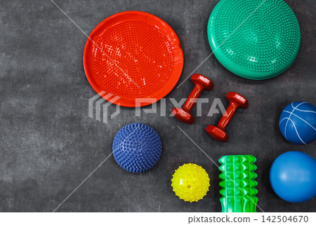 Dumbbells, fitness balls, rollers and sensory balls for physical therapy and rehabilitation in a modern rehabilitation center, top view 142504670
