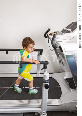Young boy is using a treadmill for therapy in a rehabilitation center. He is focused on walking 142504718