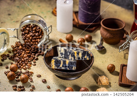Marble cheese with coffee beans, macadamia nuts, candles, and brown sugar on table Marble cheese with coffee beans, macadamia nuts, candles, and brown sugar on table 142505204
