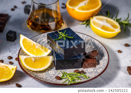 Black cheese, lemon slices, rosemary, and chocolate on decorative plate Black cheese, lemon slices, rosemary, and chocolate on decorative plate 142505221