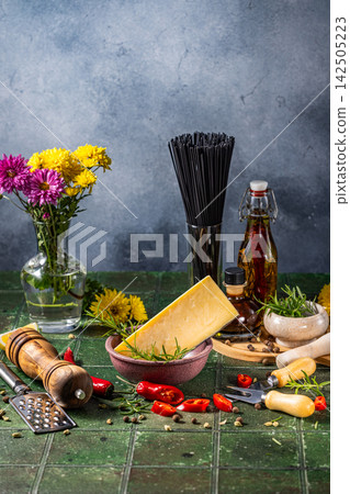 Parmesan cheese, black spaghetti, chili peppers and spices creating delicious italian dish Parmesan cheese, black spaghetti, chili peppers and spices creating delicious italian dish 142505223