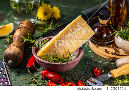 Parmesan cheese wedge with rosemary and spices on rustic kitchen table Parmesan cheese wedge with rosemary and spices on rustic kitchen table 142505224