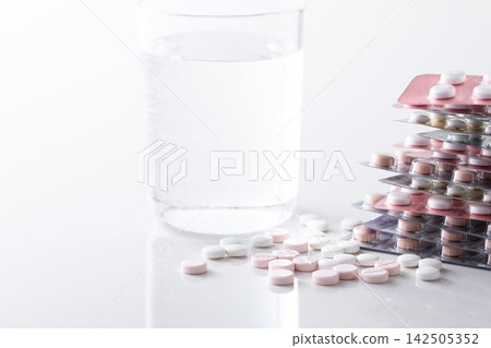 A glass of water and supplements and various medicines A glass of water and supplements and various medicines 142505352