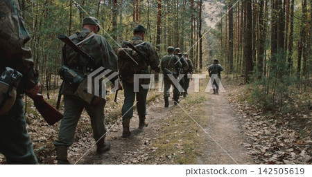Squad of WWII German infantry soldiers marching through spring forest Squad of WWII German infantry soldiers marching through spring forest 142505619