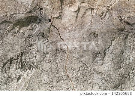 Gray beige plaster surface with deep cracks, worn areas and uneven relief creates an authentic aged texture for architectural and renovation concepts. Gray beige plaster surface with deep cracks, worn areas and uneven relief creates an authentic aged texture for architectural and renovation concepts. 142505698