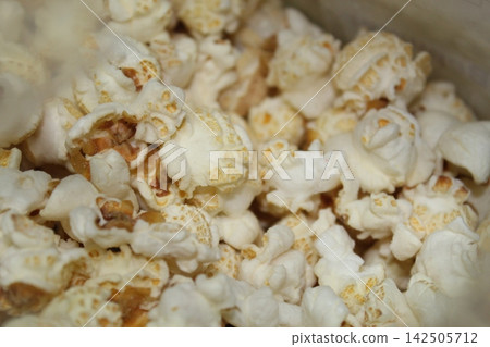 Closeup of fluffy popcorn pieces with irregular white shapes and golden areas creates an appetizing food texture suitable for culinary and snack concepts. Closeup of fluffy popcorn pieces with irregular white shapes and golden areas creates an appetizing food texture suitable for culinary and snack concepts. 142505712
