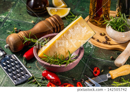 Piece of parmesan cheese with rosemary, pepper and olive oil on green table Piece of parmesan cheese with rosemary, pepper and olive oil on green table 142505742
