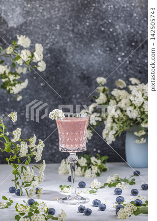 Elegant pink cocktail with blueberries and white flowers on table Elegant pink cocktail with blueberries and white flowers on table 142505743