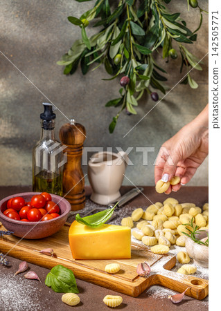 Chef placing fresh gnocchi on table with cheese, tomatoes, and olive branch Chef placing fresh gnocchi on table with cheese, tomatoes, and olive branch 142505771