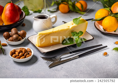 Gourmet cheese wedge with mint, fruits, and nuts on a table setting Gourmet cheese wedge with mint, fruits, and nuts on a table setting 142505792