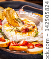 Delicious baked camembert with honey, strawberries and rosemary being dipped with toasted bread 142505824