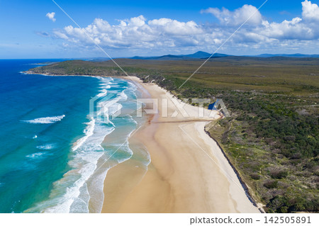 Aerial view of Angourie Bay on the NSW North Coast, featuring the sandy beach, Pacific Ocean, rocky coastline and surrounding natural landscape near Yamba in the Clarence Valley, Australia. Aerial view of Angourie Bay on the NSW North Coast, featuring the sandy beach, Pacific Ocean, rocky coastline and surrounding natural landscape near Yamba in the Clarence Valley, Australia. 142505891
