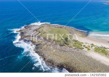 Aerial view of Angourie Point extending into the Pacific Ocean, showing the rugged rocky headland, surrounding blue waters and natural coastal landscape at Angourie on the NSW North Coast, Australia. Aerial view of Angourie Point extending into the Pacific Ocean, showing the rugged rocky headland, surrounding blue waters and natural coastal landscape at Angourie on the NSW North Coast, Australia. 142505902