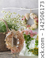 A natural floral interior decorated with roses, white flowers, and a dried flower wreath. 142506173