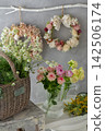 Spring flowers displayed in baskets and vases, and a flower wreath hanging on the wall. 142506174