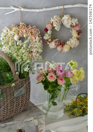 Spring flowers displayed in baskets and vases, and a flower wreath hanging on the wall. Spring flowers displayed in baskets and vases, and a flower wreath hanging on the wall. 142506174