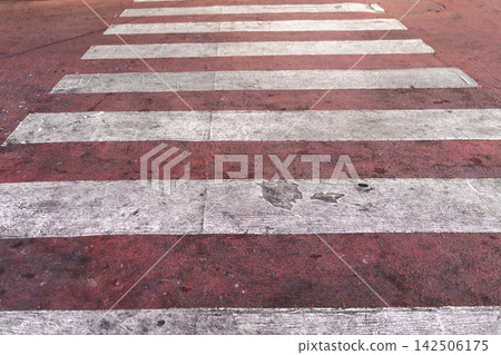Weathered Red Pedestrian Crossing with Faded White Stripes 142506175