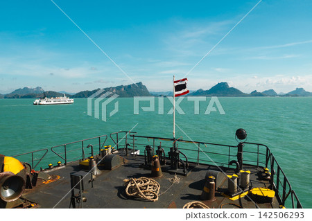Thai Flag Flying from Ferry Bow Above Turquoise Sea and Island Coastline Thai Flag Flying from Ferry Bow Above Turquoise Sea and Island Coastline 142506293