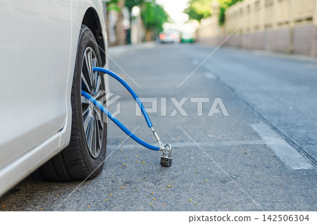 White Car Wheel Secured with Blue Cable and Padlock on Bangkok Street White Car Wheel Secured with Blue Cable and Padlock on Bangkok Street 142506304