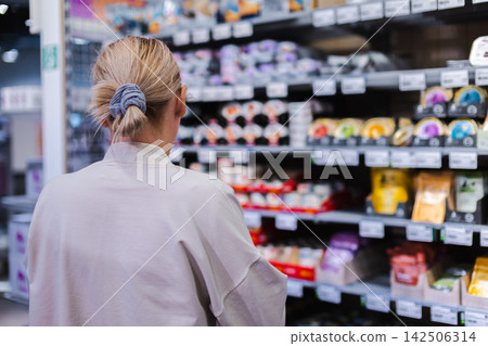 Woman Choosing Packaged Pet Food on Store Shelf Woman Choosing Packaged Pet Food on Store Shelf 142506314