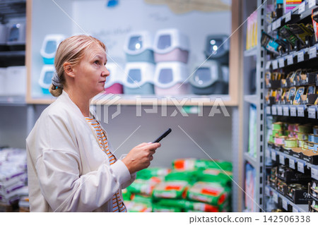 Woman Using Smartphone While Shopping for Pet Supplies Woman Using Smartphone While Shopping for Pet Supplies 142506338