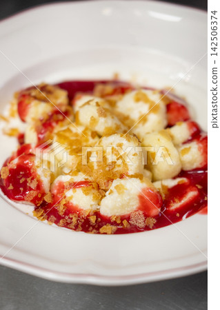 Sweet gnocchi dessert. Lazy dumplings. Tasty dish served with red berry sauce topping cereal flake on white plate. Appetizing curd balls with jam. Sweet gnocchi dessert. Lazy dumplings. Tasty dish served with red berry sauce topping cereal flake on white plate. Appetizing curd balls with jam. 142506374