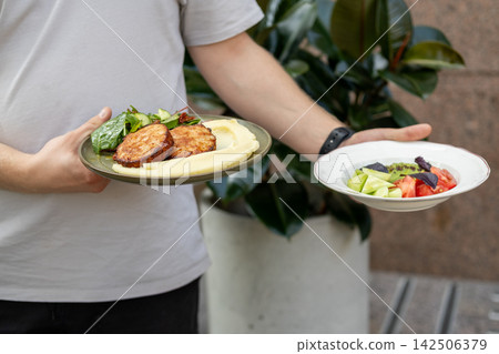 Waiter service. Restaurant workflow. Man holding plate with appetizing healthy dinner. Cafeteria lunch with meat fresh vegetable slice. Waiter service. Restaurant workflow. Man holding plate with appetizing healthy dinner. Cafeteria lunch with meat fresh vegetable slice. 142506379