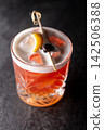 Alcoholic drink. Aperitif glass. Bright red new york sour cold cocktail with white foam garnished with olive lemon on pub counter. 142506388