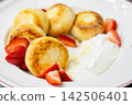 Cottage cheese pancakes. Sweet breakfast. Traditional fried syrniki served on white plate with sour cream honey sliced fresh strawberry. 142506401