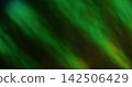 Defocused twinkle. Abstract glare. Blur green color foil texture optical flare rainbow light round flash on bokeh dark black background. 142506429