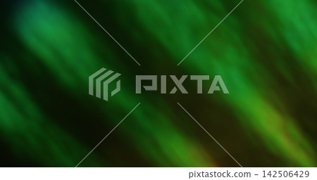Defocused twinkle. Abstract glare. Blur green color foil texture optical flare rainbow light round flash on bokeh dark black background. 142506429