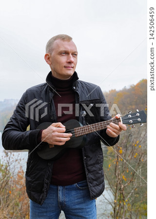 Human interaction with wooden musical instrument ukulele guitar, emphasizing leisure creativity and personal expression. Concept of peaceful environment mood of outdoor recreation and acoustic music Human interaction with wooden musical instrument ukulele guitar, emphasizing leisure creativity and personal expression. Concept of peaceful environment mood of outdoor recreation and acoustic music 142506459