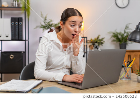 Young businesswoman gets thank you email on laptop covers mouth in delight and smiles with happy joy Young businesswoman gets thank you email on laptop covers mouth in delight and smiles with happy joy 142506528