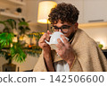 Arabian man sick with sore throat drinks hot tea with medicine uses paper tissues at night indoors 142506600