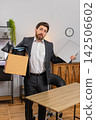 Middle-aged businessman packs personal items in box looks around room with gentle nostalgia softly 142506602