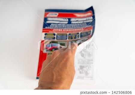 Hand turning a page of a brochure for cars at a table Hand turning a page of a brochure for cars at a table 142506806