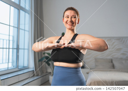 Fitness workout training. Woman practicing fitness at home. Plus size female doing sports exercise at home indoor. Girl in sportswear have workout weight training for weight loss. Sport and fitness Fitness workout training. Woman practicing fitness at home. Plus size female doing sports exercise at home indoor. Girl in sportswear have workout weight training for weight loss. Sport and fitness 142507047