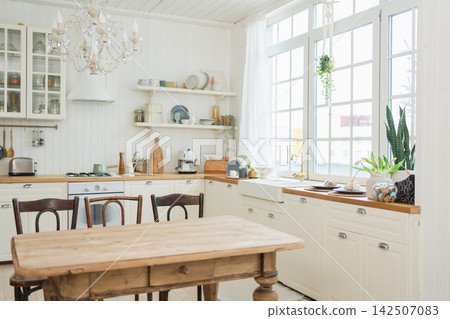 Empty white wooden kitchen interior with dining room. Scandinavian classic minimalistic bright kitchen with white and wooden details. Modern white kitchen clean contemporary style interior design 142507083