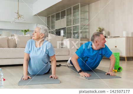Fitness training. Senior mature healthy fit couple doing sports exercise at home. Mid age husband wife have training workout. Health care healthy lifestyle. Workout rehabilitation for old man woman Fitness training. Senior mature healthy fit couple doing sports exercise at home. Mid age husband wife have training workout. Health care healthy lifestyle. Workout rehabilitation for old man woman 142507177