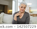 Sad tired ill sick lonely disappointed older senior woman sitting at home alone. Unhappy mature grandmother experiencing grief relative death bad news. Stressed elder lady suffering from loneliness 142507229
