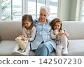 Happy family at home. Two little girls sisters twins grandmother enjoying time together. Good time at home. Grandma granddaughters child kids emotional bonding hugging together. Family generations 142507230
