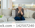 Sad tired ill sick lonely disappointed older senior woman sitting at home alone. Unhappy mature grandmother experiencing grief relative death bad news. Stressed elder lady suffering from loneliness 142507240