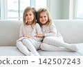 Happy family sisterly love. Two funny little twin sisters girls hugging with love care playing together at home indoors. Happy children lifestyle. Identical twin girls hugs. Girls friendship and youth 142507243