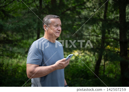 Senior man using smartphone with wireless earbuds outdoors Senior man using smartphone with wireless earbuds outdoors 142507259