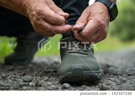 Senior man tying running shoe outdoors Senior man tying running shoe outdoors 142507288