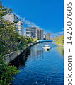 A ship sailing under a blue sky and a city waterfront landscape. 142507605