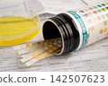 Urinalysis, urine cup with reagent strip pH paper test and comparison chart in laboratory. 142507623