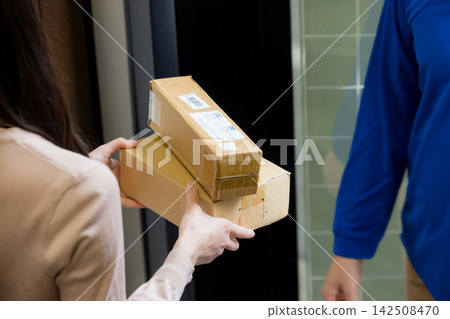 Delivery person handing over the package at the front door Delivery person handing over the package at the front door 142508470