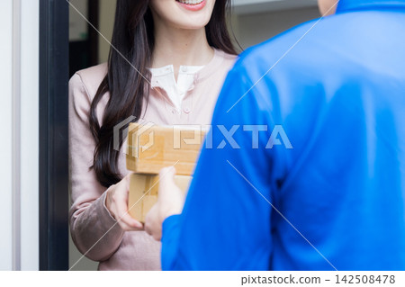 Delivery person handing over the package at the front door 142508478