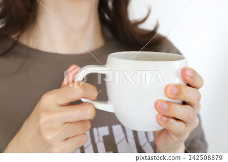 一位女士正在喝熱飲取暖。 142508879